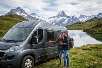 Jeune couple discutant devant un van en montagne