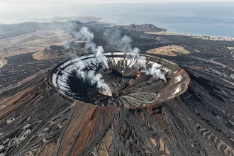 Vue aérienne drone du cratère sommital de l'Etna avec panaches de gaz volcaniques et champs de lave noire en Sicile