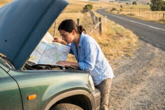 Femme consultant une carte routière dépliée sur le capot d'un SUV lors d'un road trip à la campagne